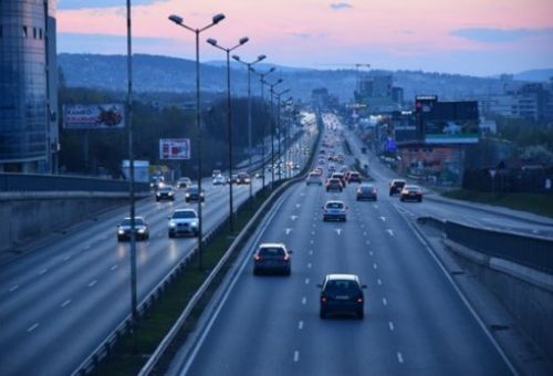 Imagen de una carretera con tres carriles y coches circulando por ella por una ciudad