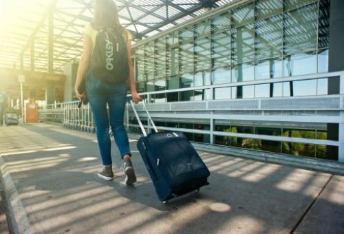 Chica con mochila y maleta andando por el aeropuerto